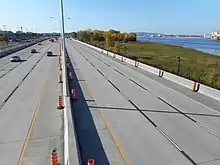 Une autoroute longe un fleuve, avec une ville en arrière-plan.