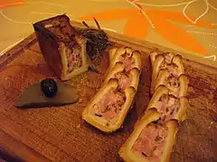 Pâté en croûte cocktail aux morilles, présenté tranché avec une olive posée sur un cornichon.