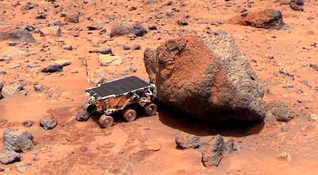 Photo du rover appliquant le spectromètre APXS sur le rocher Yogi.