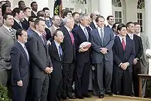 Assemblée sur plusieurs rangs posant pour les journalistes, le président Bush, au centre, tenant un ballon.