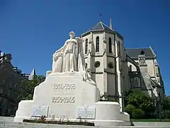 Photographie en couleurs d'un monument aux morts devant une église.