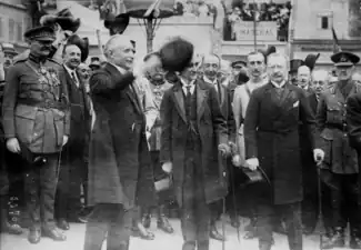 Photo en noir et blanc d’un homme saluant la soule, avec derrière lui des officiels en rangs serrés