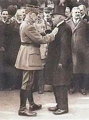 Photo noir et blanc du maréchal Foch remettant la médaille de chevalier de la Légion d’honneur à Paul Michaux devant la foule.