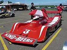 Photographie d'une voiture de sport-prototype rouge avec de fins traits blancs, vue de trois-quarts.