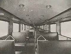 Photographie en noir et blanc montrant l'intérieur de l'autorail avec plusieurs rangées de sièges alignés.