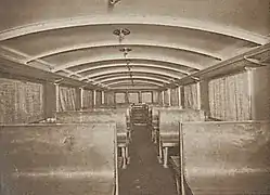 Photographie en sépia de plusieurs sièges d'allure rustique et peu confortable dans un autorail.