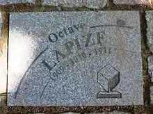 Photographie d'un pavé gris portant l'inscription « Octave Lapize 1909-1910-1911 ».