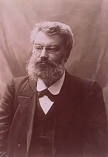 Photo monochrome d'un homme barbu portant un monocle.