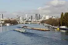 Quatre petites barges et une grande barge de sable le long du bois de Boulogne.