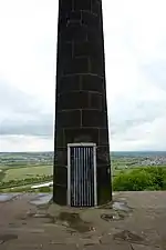 Une porte dans une colonne de pierre, recouverte d'une grille métallique