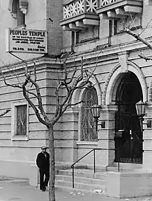 Une porte et un panneau indiquant les horaires des services du Temple du Peuple de Jim Jones.