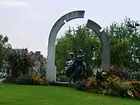 Cœur fleuri du rond-point, avec une sculpture représentant deux personnes surplombées par une arche en deux parties.