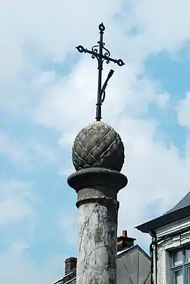 La pomme de pin et la croix en fer qui surmontent le perron.