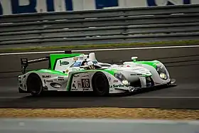 Photographie d'une voiture de sport-prototype blanche, verte et noire, vue de trois-quarts, sur une piste.