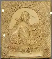 Morceau d'ivoire avec de riches gravures, représentant un monarque au centre d'un cadre ovale décoré.