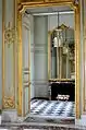 Vue de l'antichambre depuis le salon central montrant le miroir du fond et le dallage de marbre.