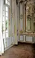 Vue du boudoir depuis le salon central montrant les miroirs dorés et le parquet Versailles.