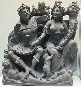 Le couple protecteur Panchika et Hariti (à la corne d'abondance) : réminiscence classique (méditerranéenne antique), IIe – IIIe siècle. Schiste. British Museum (provenance Takht-i-Bahi).
