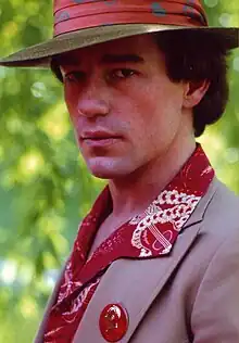 Photo de Phil Hartman habillé comme son personnage de Chick, chapeau rose, veste mauve et chemise rouge