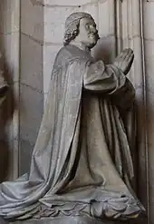Statue de trois-quart d'un homme agenouillé et priant