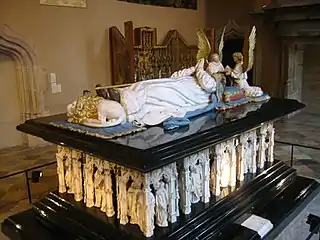 Vue de trois-quart d'un tombeau, avec au-dessus un gisant, à ses pieds un lion couché
