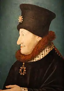Buste du duc tourné vers la gauche vêtu d'un manteau à col fourré rouge et bonnet noir.