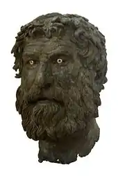 tête d'un homme barbu et les cheveux mal coiffé, en bronze, avec deux yeux très blancs