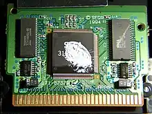 Photo du microprocesseur du jeu Virtua Racing, doté au centre du Sega Virtua Processor, ici taché de blanc