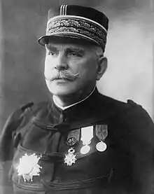 Photographie en buste d'un officier moustachu portant un képi à feuilles de chêne, un dolman à brandebourgs et quatre décorations.