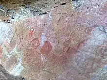 Dessins géométriques peints en rouge sur une pierre