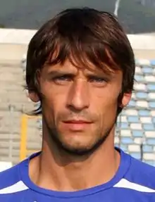 Cou et visage d'un homme de face. Pose sur un terrain de football, tribune en arrière-plan.