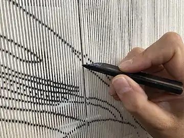 Le licier trace les contours du motif à tisser.