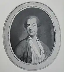 Photo noir et blanc. Portrait de face d'un homme portant une perruque courte, chemise largement ouverte sur la poitrine.