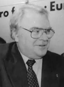 Photographie en noir et blanc du visage vu de trois-quarts droit d'un homme cravaté et portant des lunettes