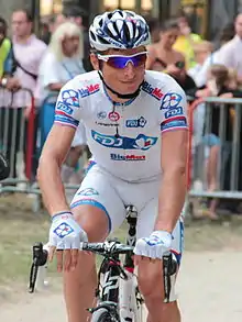 Photographie d'un cycliste vêtu de blanc, sur son vélo, vu de face.