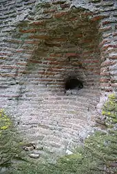 Vue d'une cavité pratiquée dans un massif de briques montrant, au fond, un noyau en pierres.