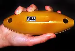 Un objet fusiforme jaune de la dimension de la main qui le tient.