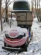 Photographie d'un petit véhicule avec un sourire, des lunettes et un chapeau.