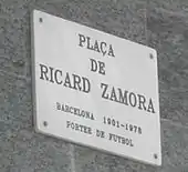 Photographie d'un panneau blanc, indiquent la place Ricardo-Zamora.