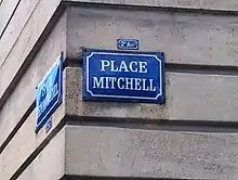 Plaque de rue avec l'inscription "Place Mitchell" en blanc sur fond bleu