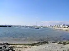 Le port d'échouage, à l'extrémité orientale de la baie du Pouliguen bordée à droite de l'image, par le ruban de sable de la plage des Libraires, qui se prolonge, au loin et à gauche, par la plage de La Baule. (Vue estivale).