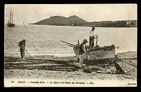 Carte postale noir et blanc. Barque sur la grève avec un deux mâts dans une baie bordée de montagnes.