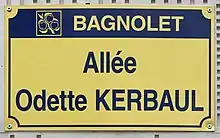 Photo d'une plaque de rue portant la mention « Allée Odette Kerbaul » sur fond jaune.