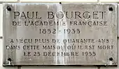 Plaque de marbre fixée sur un mur rappelant le souvenir de Paul Bourget.
