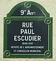 Plaque de tôle émaillée conforme à la réglementation de 1982. Un court texte indique l'origine du nom ou présente le personnage honoré