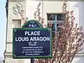 La plaque de rue de la place Louis-Aragon avec, au fond, un bâtiment du quai de Bourbon.