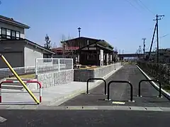 Ici, la plateforme a été goudronnée autour de la gare, dont le bâtiment et les quais subsistent.