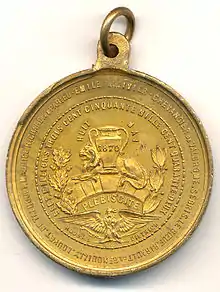 Liste des noms de personnalités politiques inscrite de façon circulaire sur le revers de la médaille dorée. Au centre aigle impérial et vase avec inscription 1870. Un crochet pour pendre la médaille est fixé sur le dessus de celle-ci.