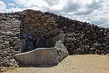 Polygone dessiné par de gigantesques pierres debout, dont une partie est hors du cairn. Mais elles ne sont pas couvertes d'une table. À l'arrière, on voit les maigres restes de la voûte en encorbellement.