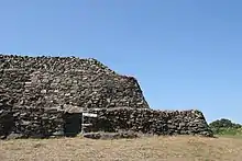 extrémité est du cairn. La partie couverte du couloir est murée.